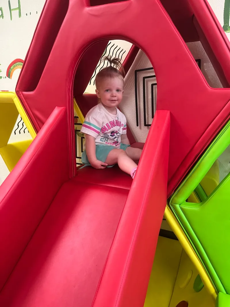 Young child enjoying a slide indoors